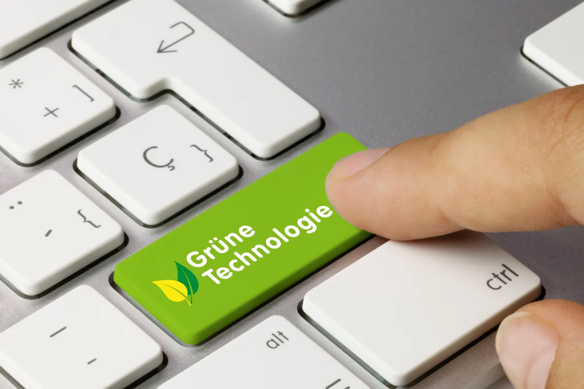 Blick auf eine Somputertastatur - eine Hand drückt eine grün gefärbte Taste mit der Aufschrift "Grüne Technologie"